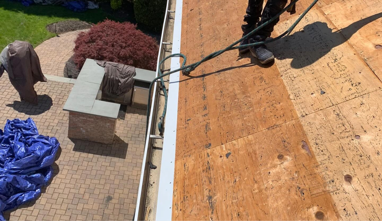 An expert contractor working near a service truck to customize aluminum materials for a high-quality house gutter installation.