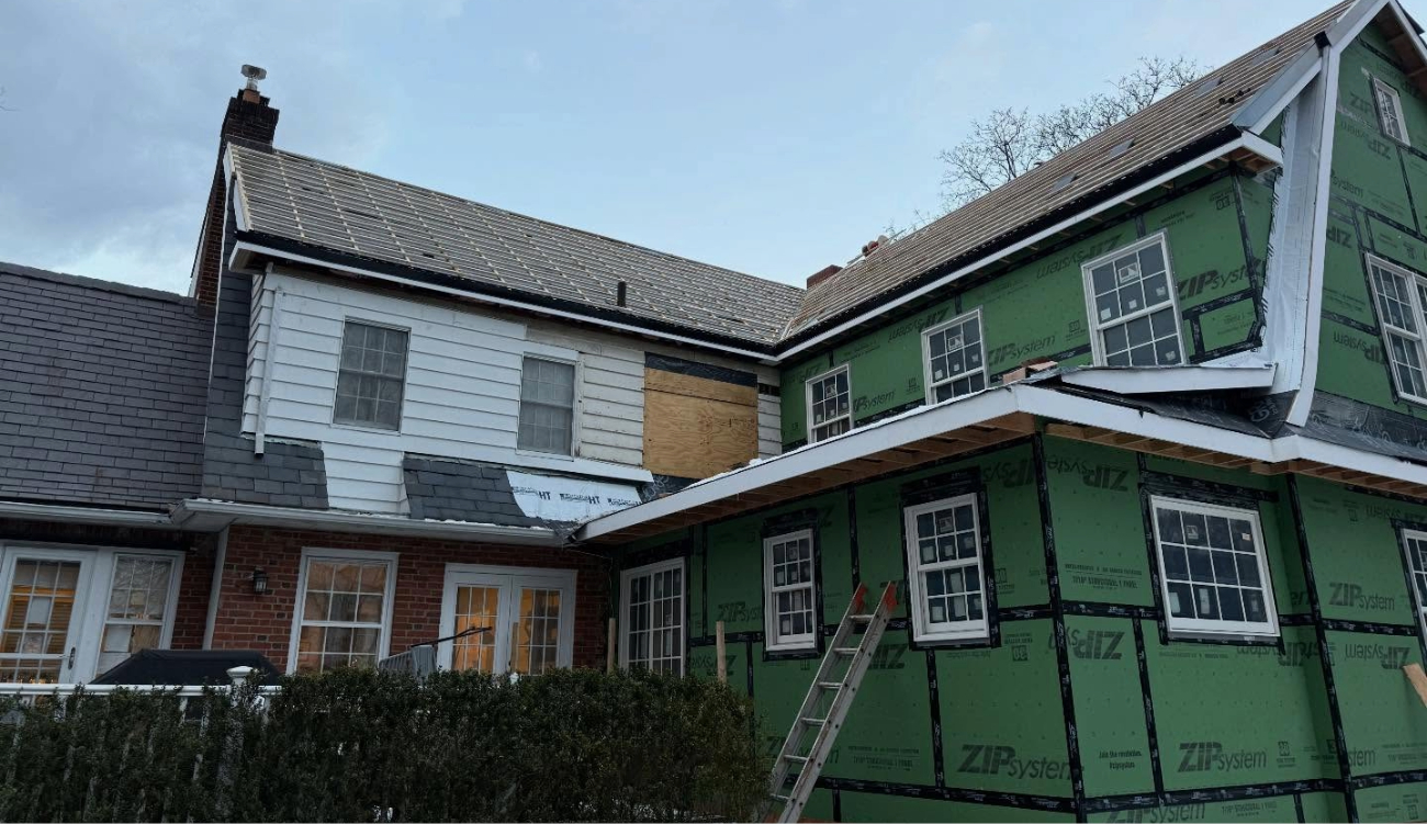 high-angle drone shot showing diverse roof sections on a large home, illustrating a comprehensive approach to roof maintenance.