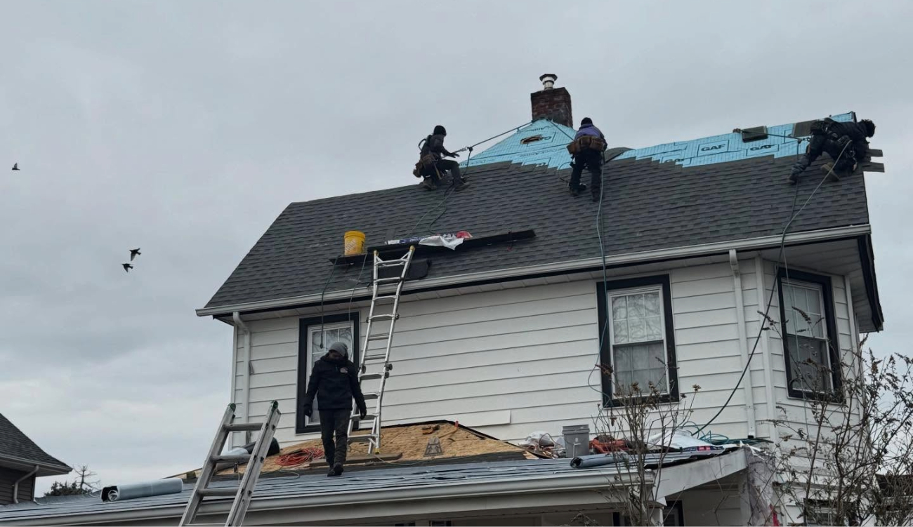 Multiple roofers using safety harnesses on a steep residential roof performing a flashing repair.