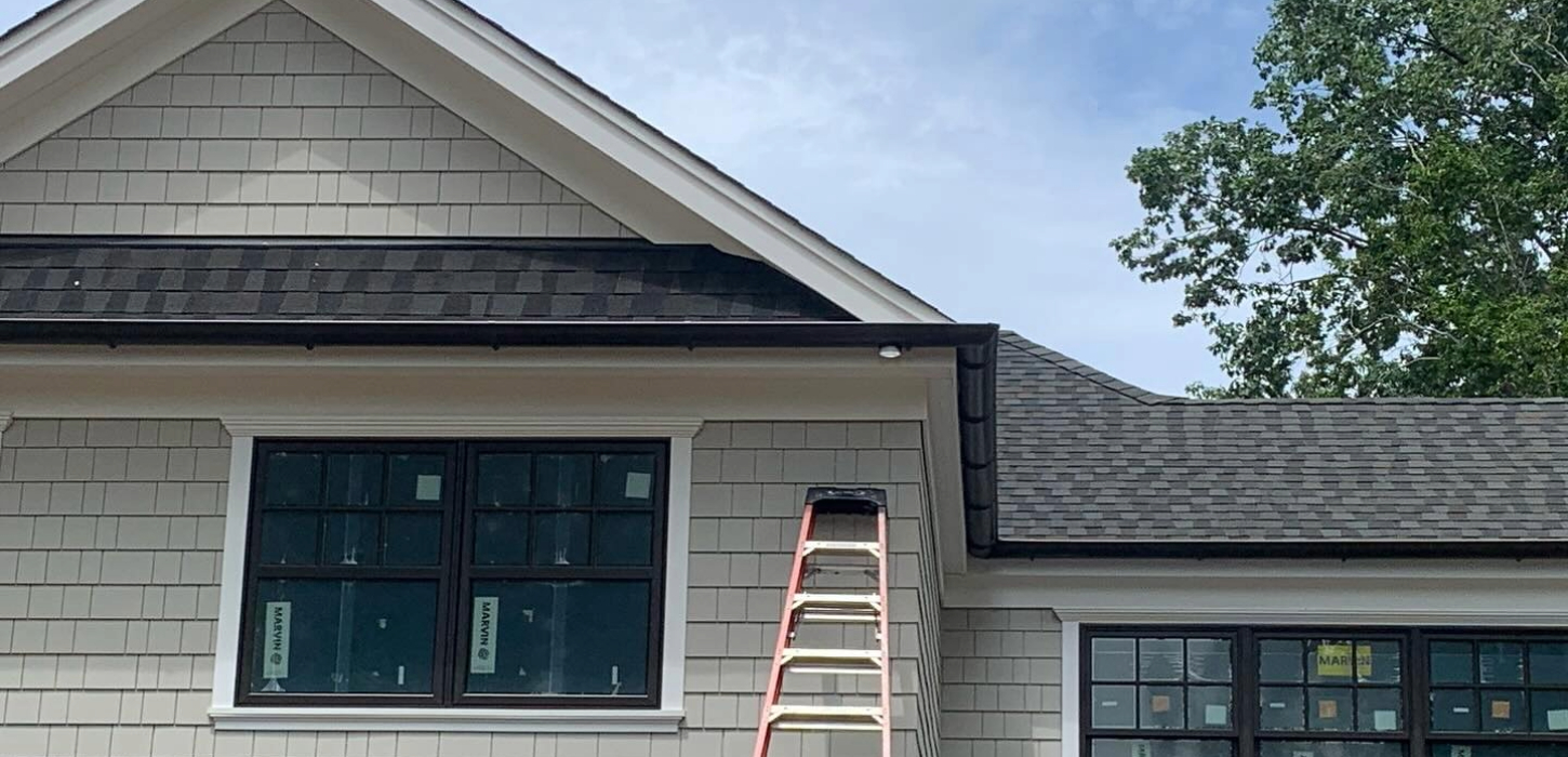 A close-up of a clean, tan-colored aluminum gutter section ready for a professional house gutter installation project.