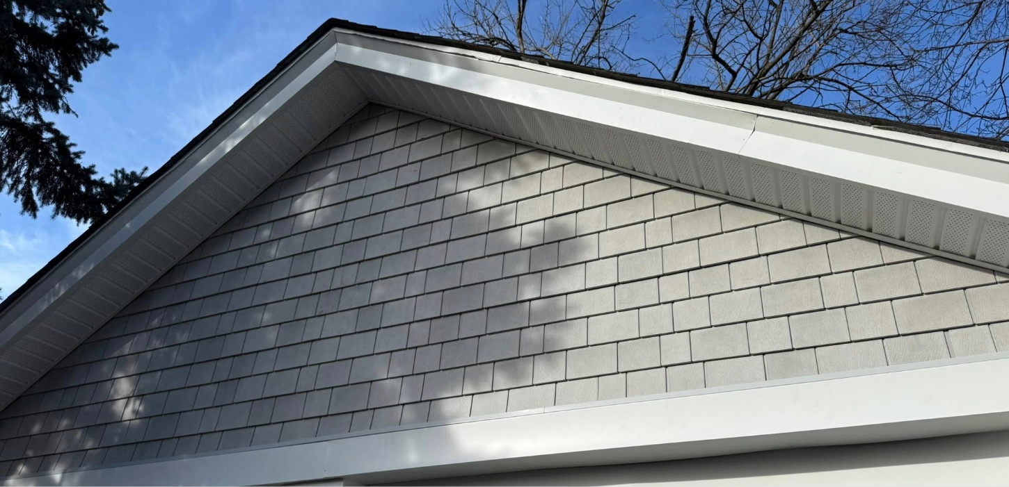 A close-up view of newly installed white perforated vinyl panels, ensuring proper ventilation during a soffit repair.