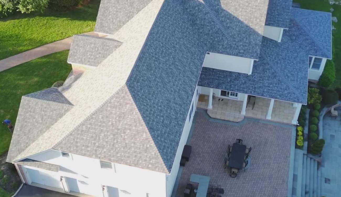 This aerial view of a sprawling residential property highlights various structural features and clear signs you need a new roof.