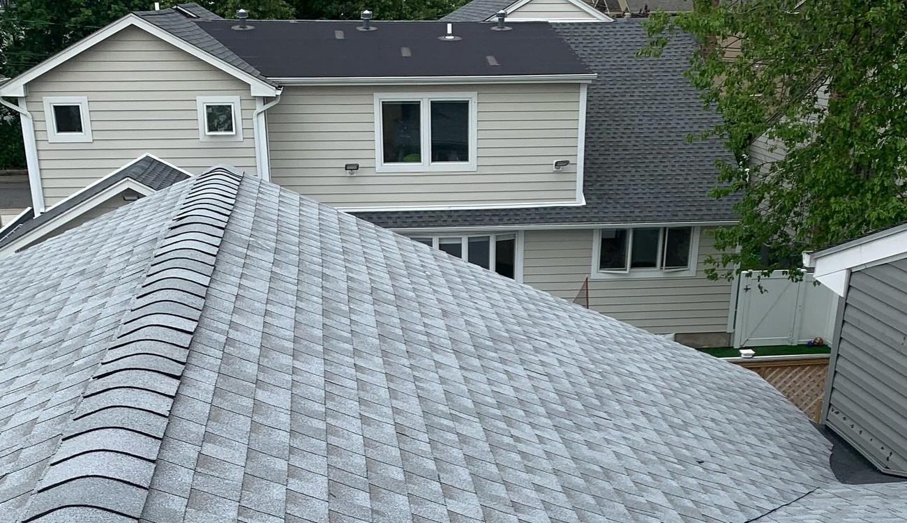 High-angle view of crisp, light gray architectural shingles from a recent roof replacement in Long Island.