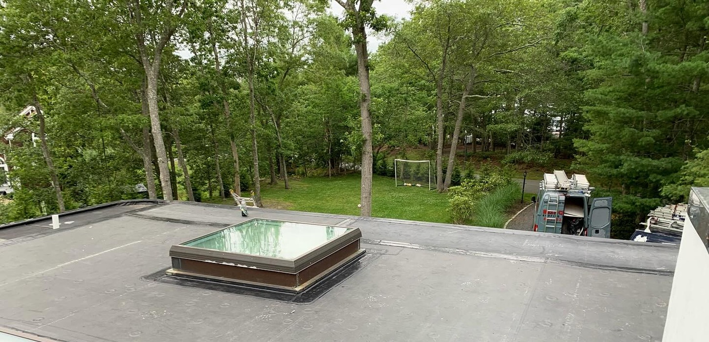 A flat commercial roof with a large skylight during a roof replacement in New York.