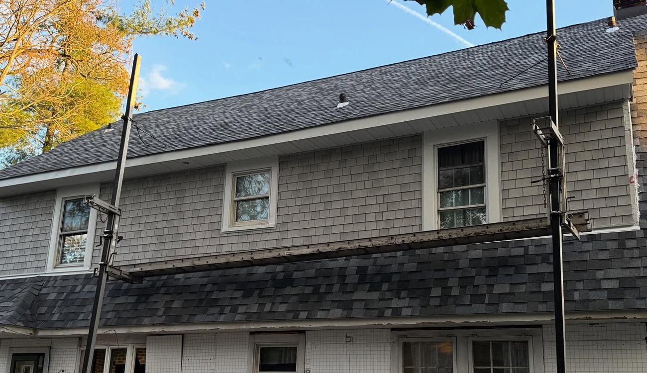 A house featuring a newly completed storm damage roof replacement Nassau County with scaffolding still in place.
