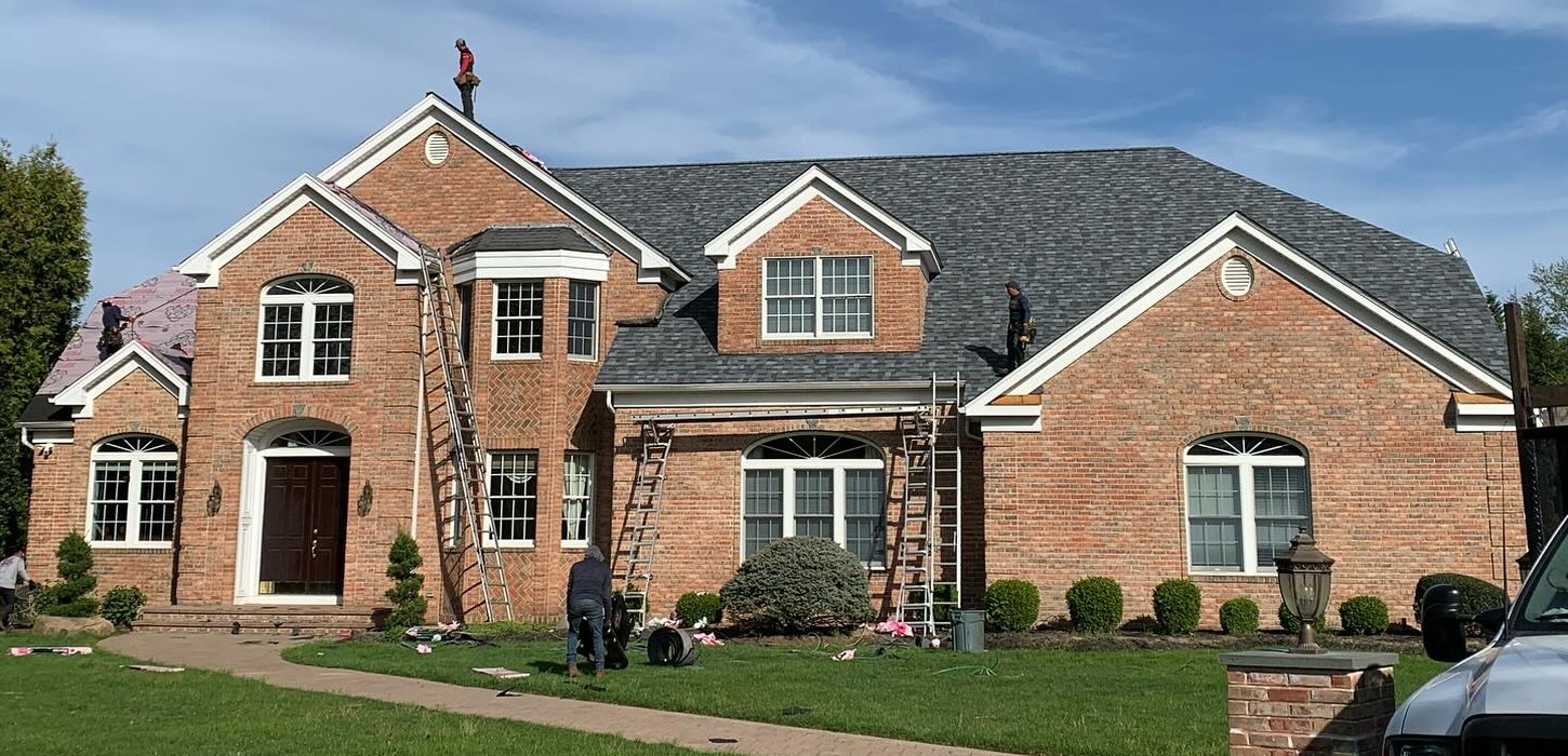 Contractors installing new architectural shingles during a full roof replacement in Garden City