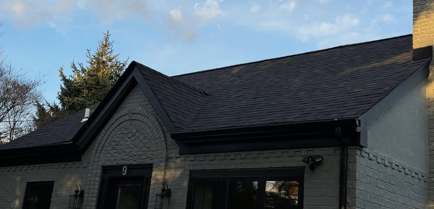 A worker layering underlayment and shingles during a roof replacement in Hicksville.
